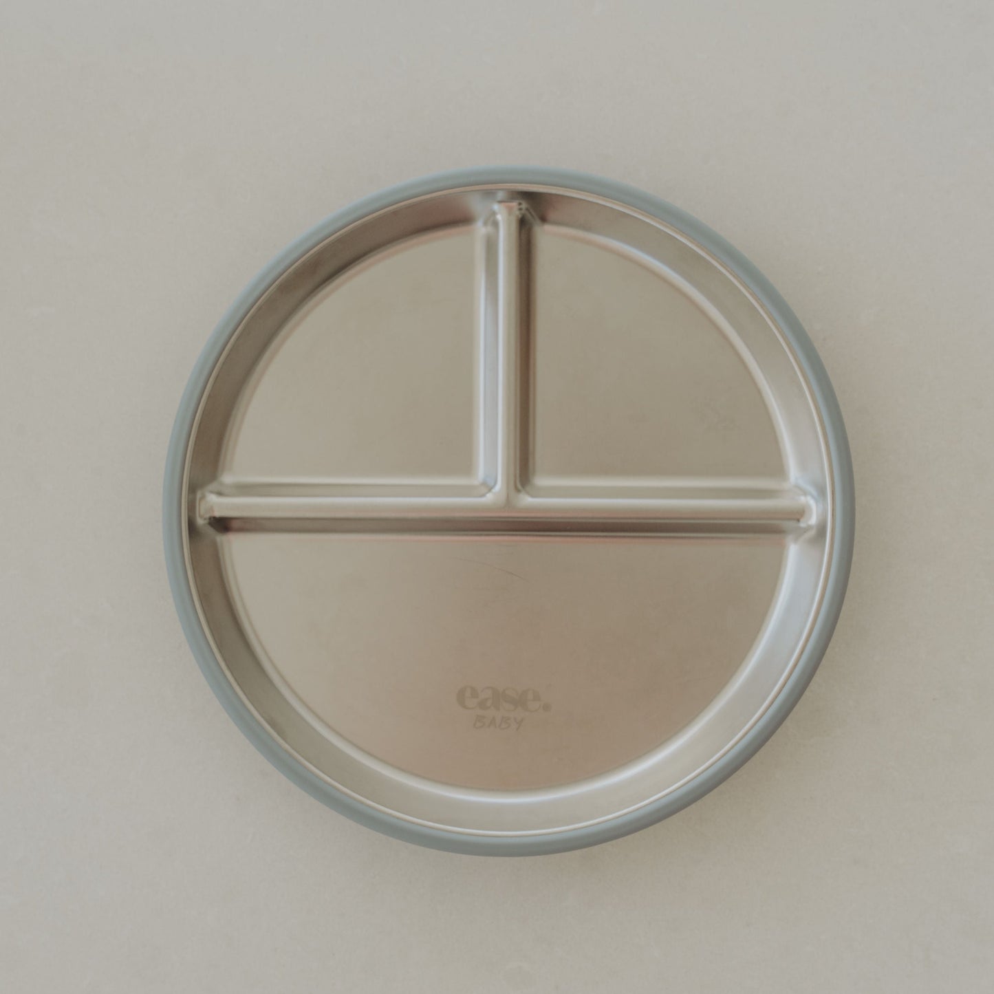 Round stainless steel plate with three sections on a beige background