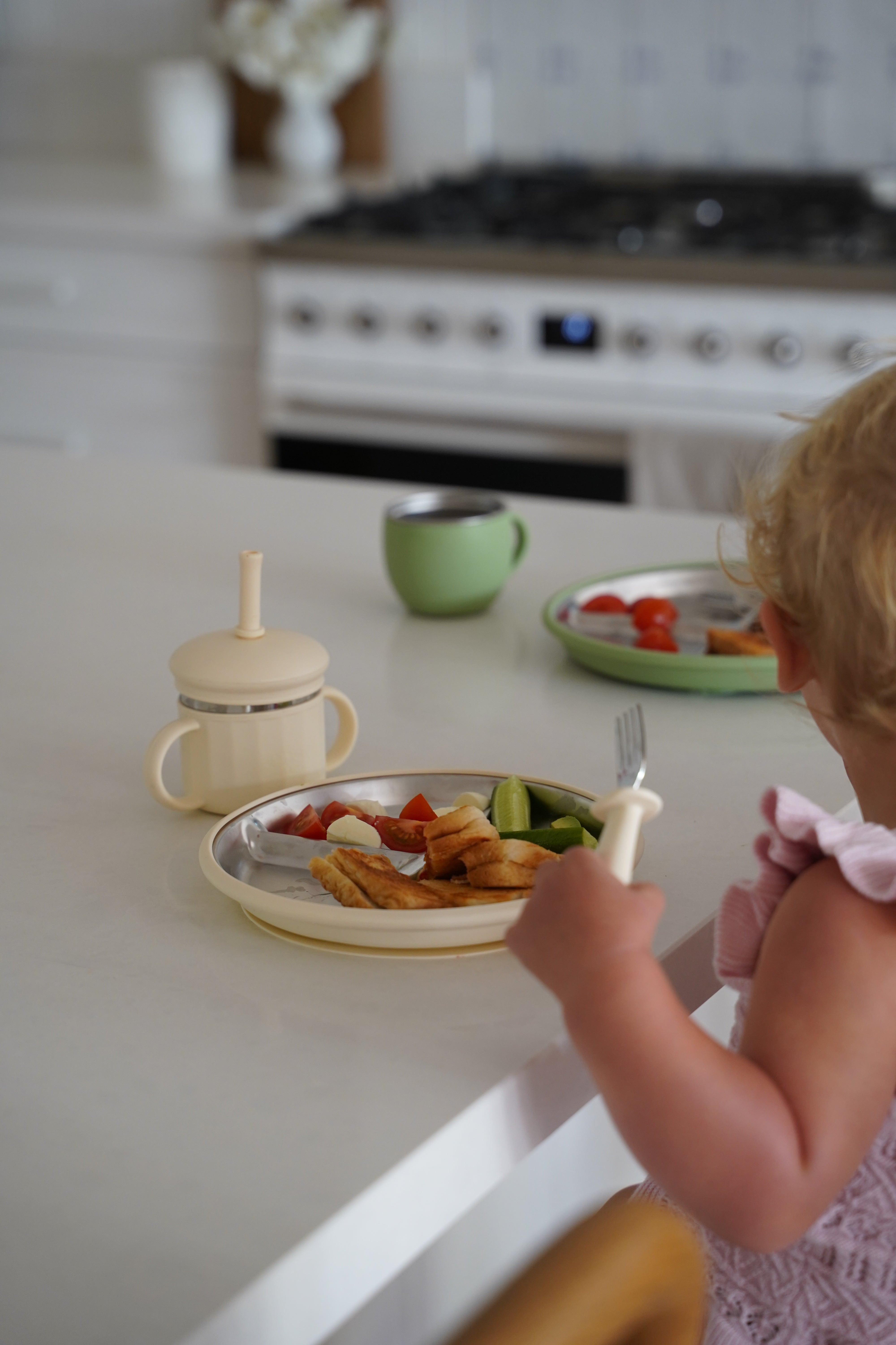 Child eating from a bowl with a spoon in a kitchen setting
