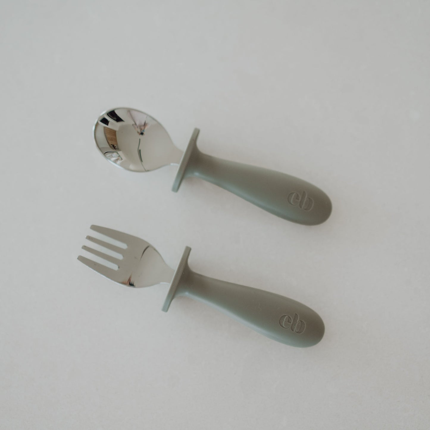 Spoon and fork with green handles on a white background