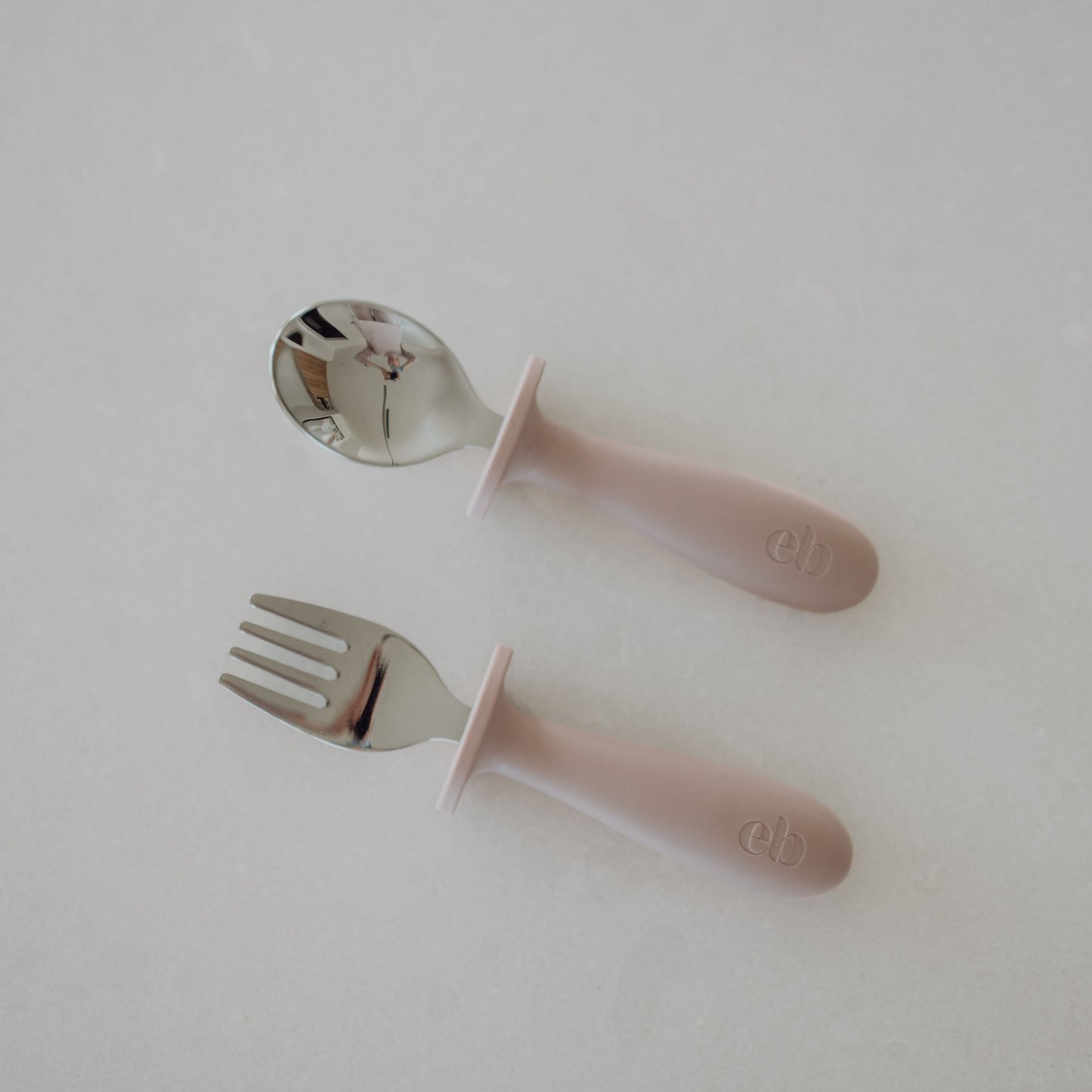 Pink children's fork and spoon set on a light gray background