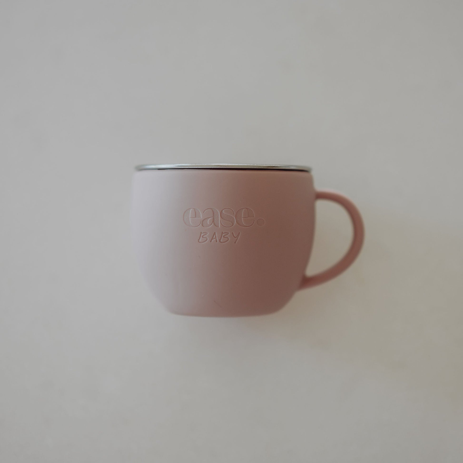 Pink mug with 'ease baby' branding on a light gray background