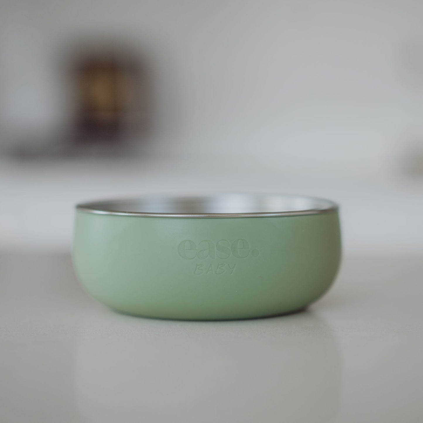 Green Stainless Steel bowl with 'ease' branding on a blurred background