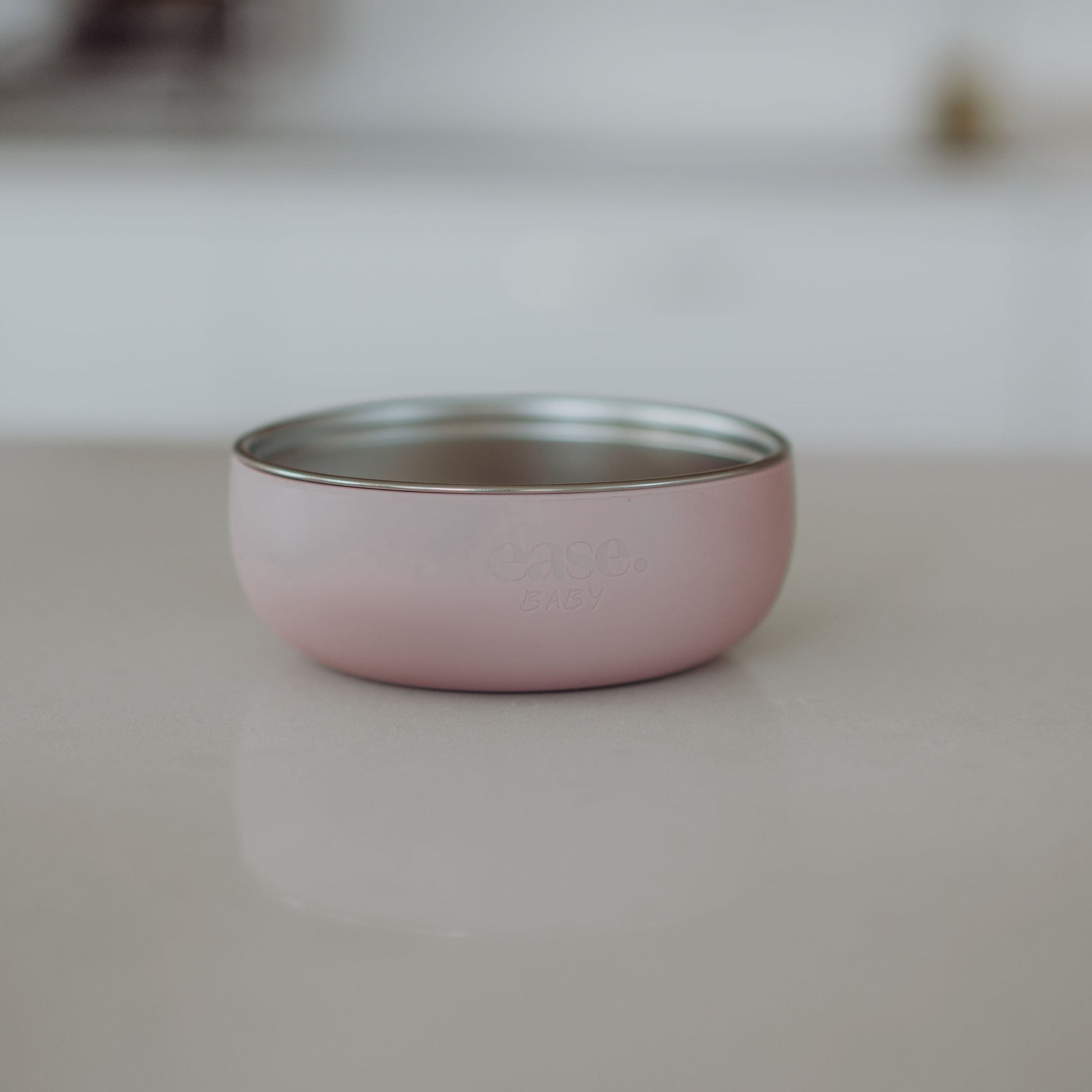 Pink Stainless Steel bowl with silver interior on a light gray surface