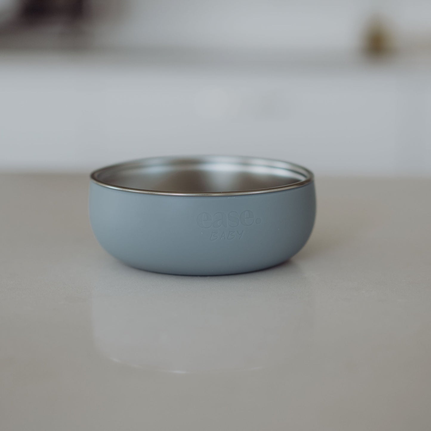 Blue Stainless Steel bowl on a white surface with a blurred background