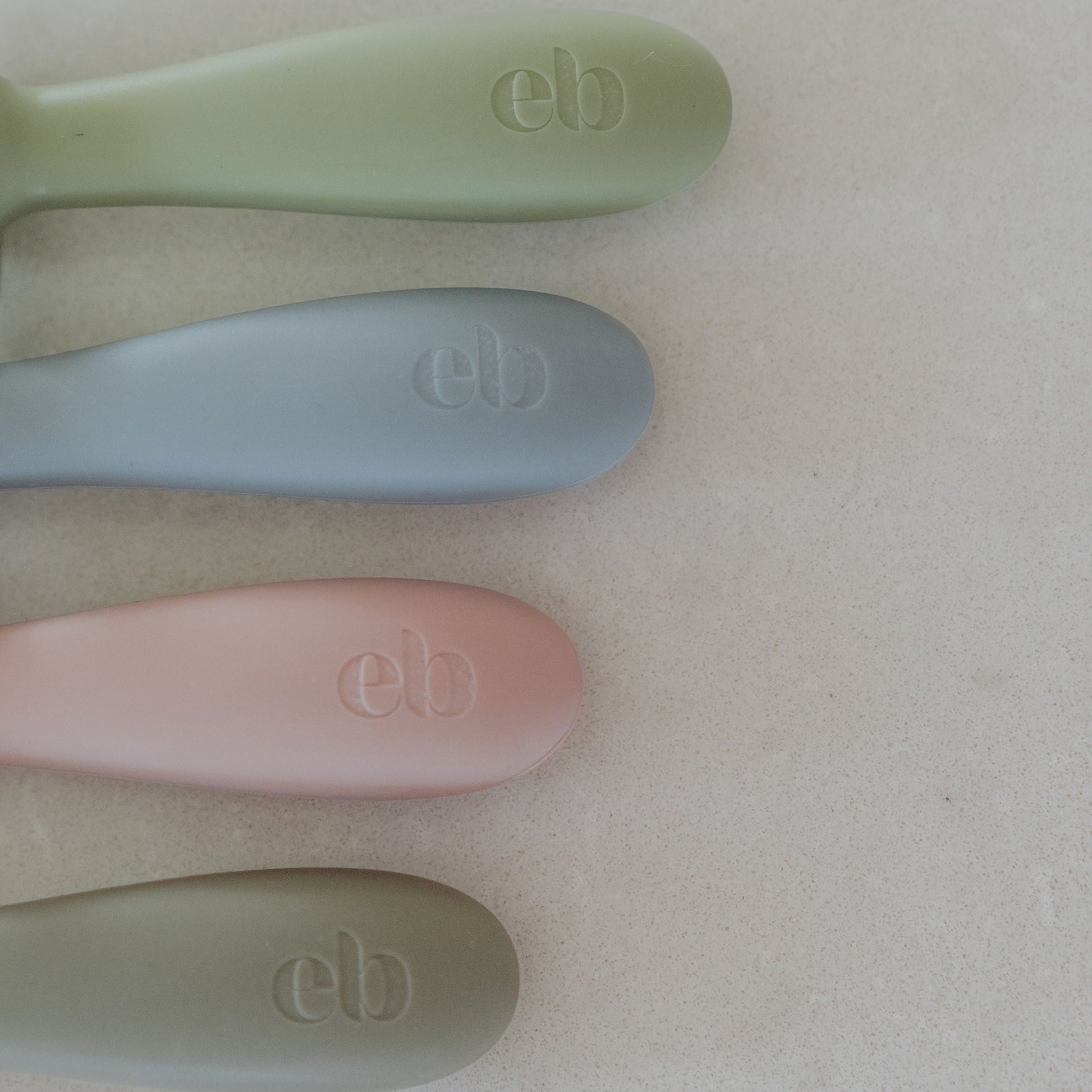 Four baby spoons with 'eb' branding on a light background