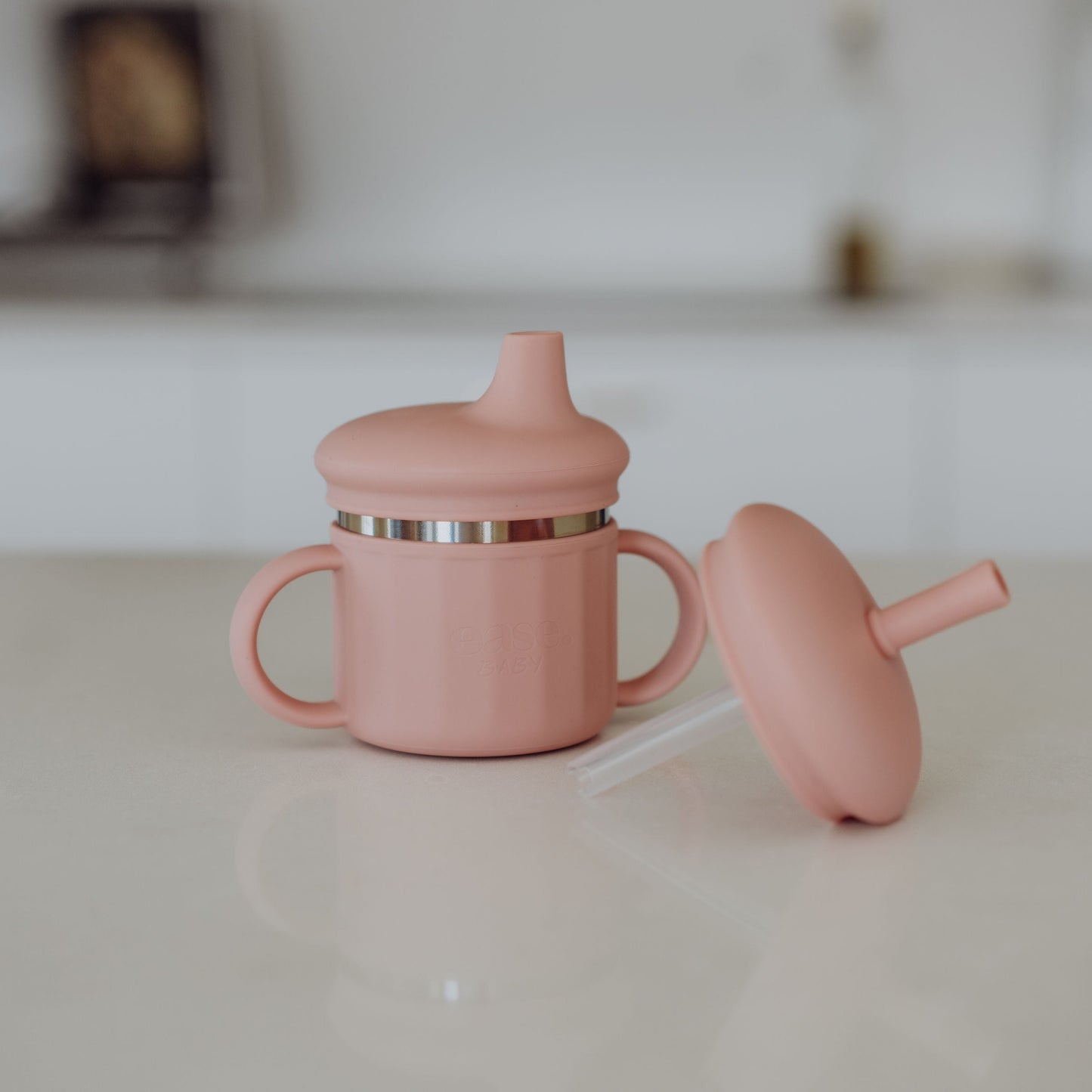 Pink sippy cup with a lid on a kitchen counter