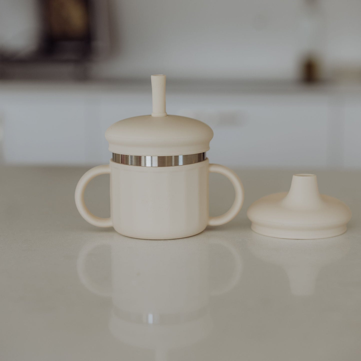 White stainless steel sippy cup with lid on a white surface