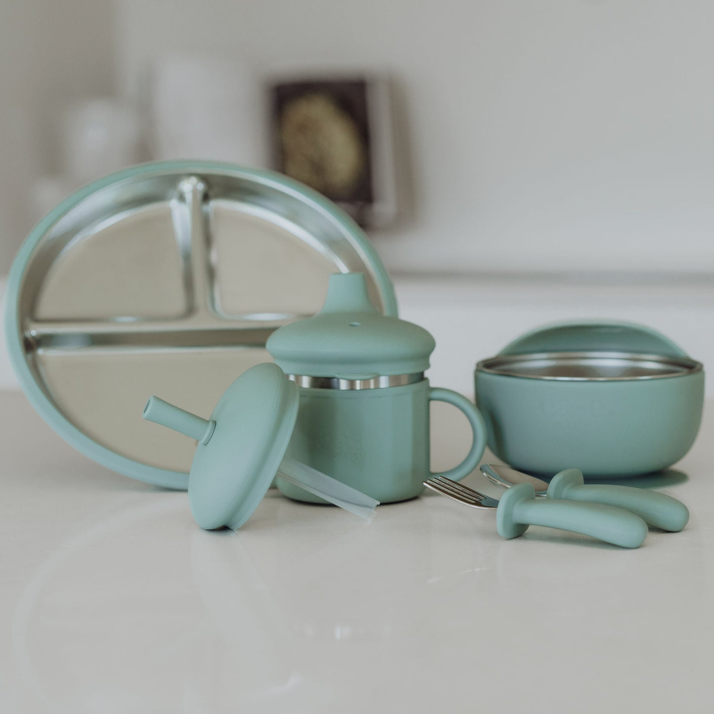 Set of turquoise kitchen utensils including a whisk, measuring cups, and bowls on a white surface.