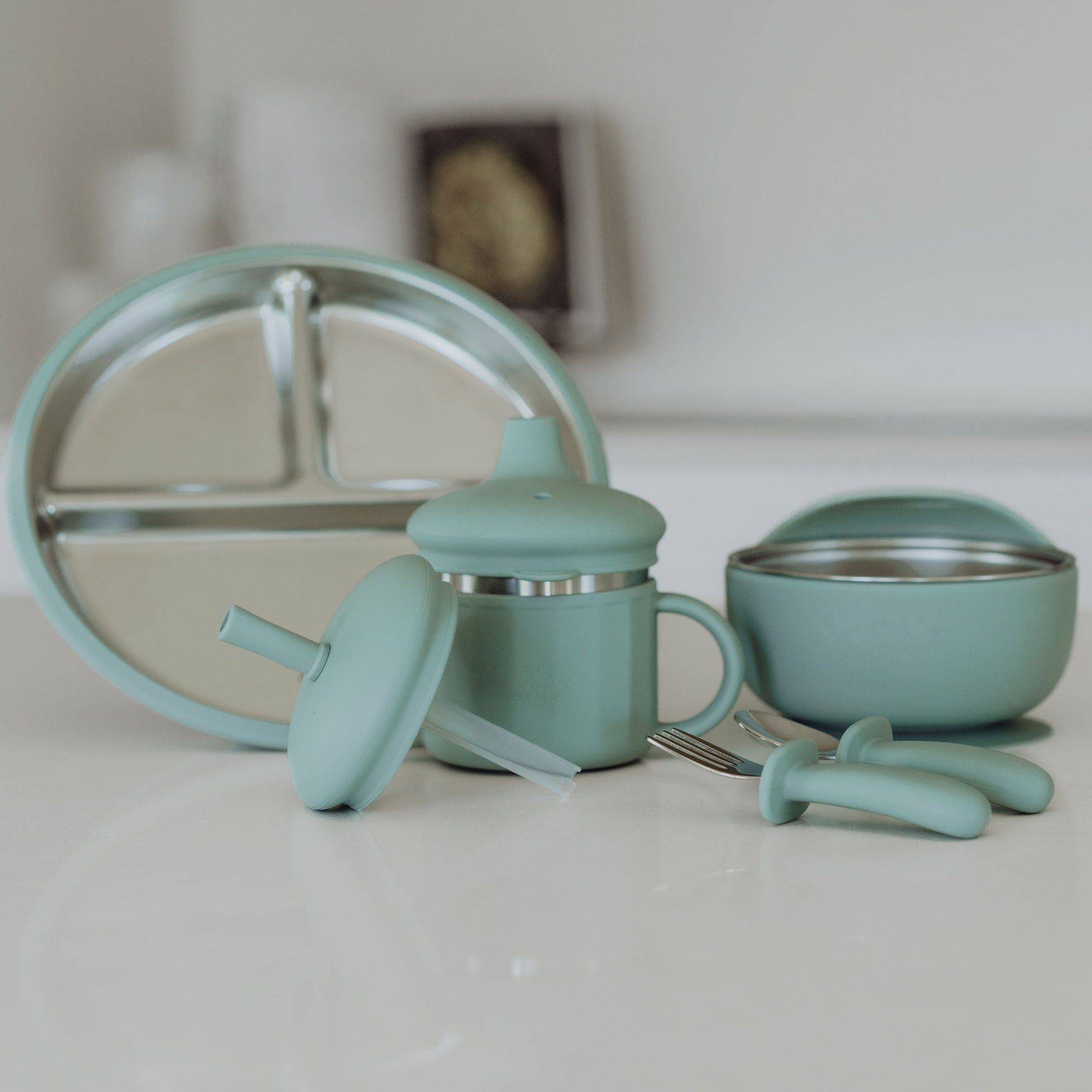 Set of turquoise kitchen utensils including a whisk, measuring cups, and bowls on a white surface.
